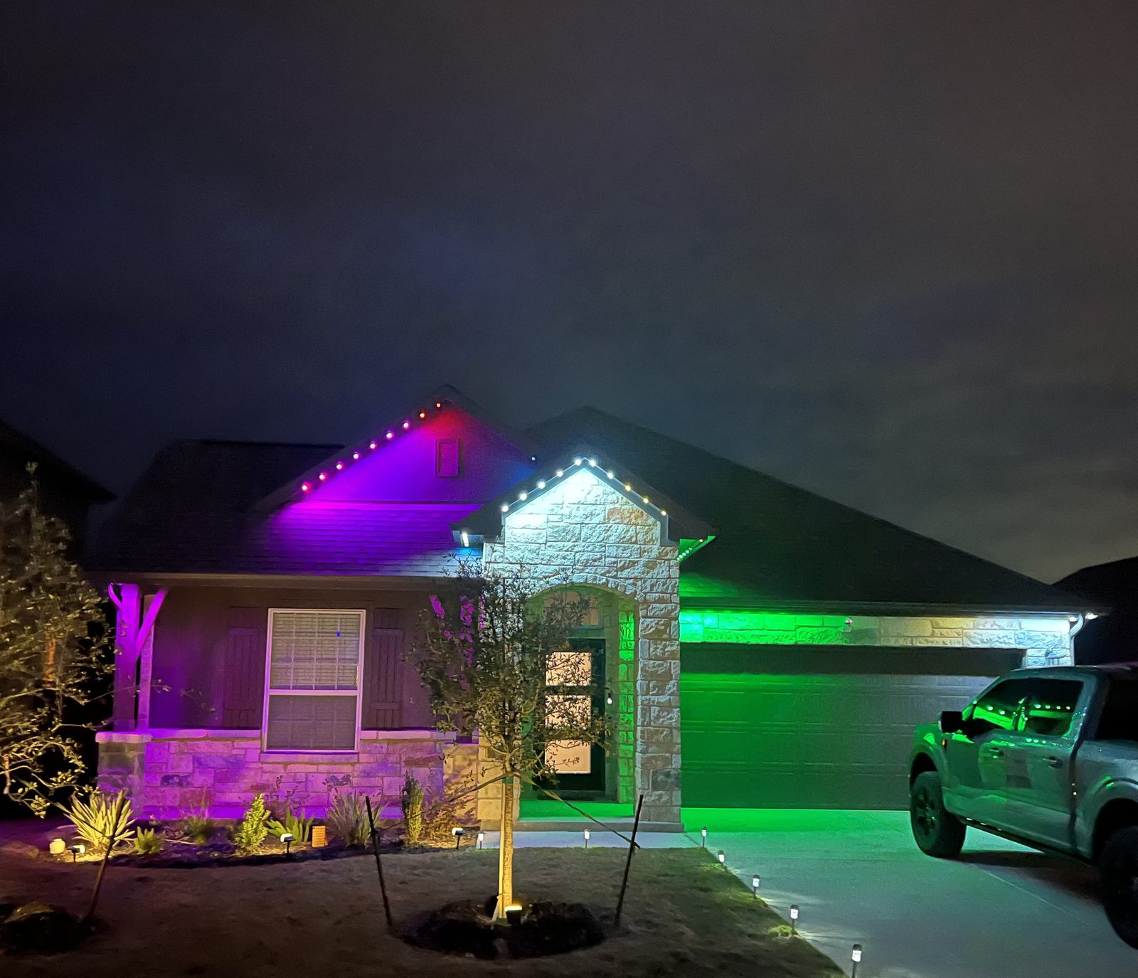 Crisp warm white roofline lighting following the gables of a natural stone home