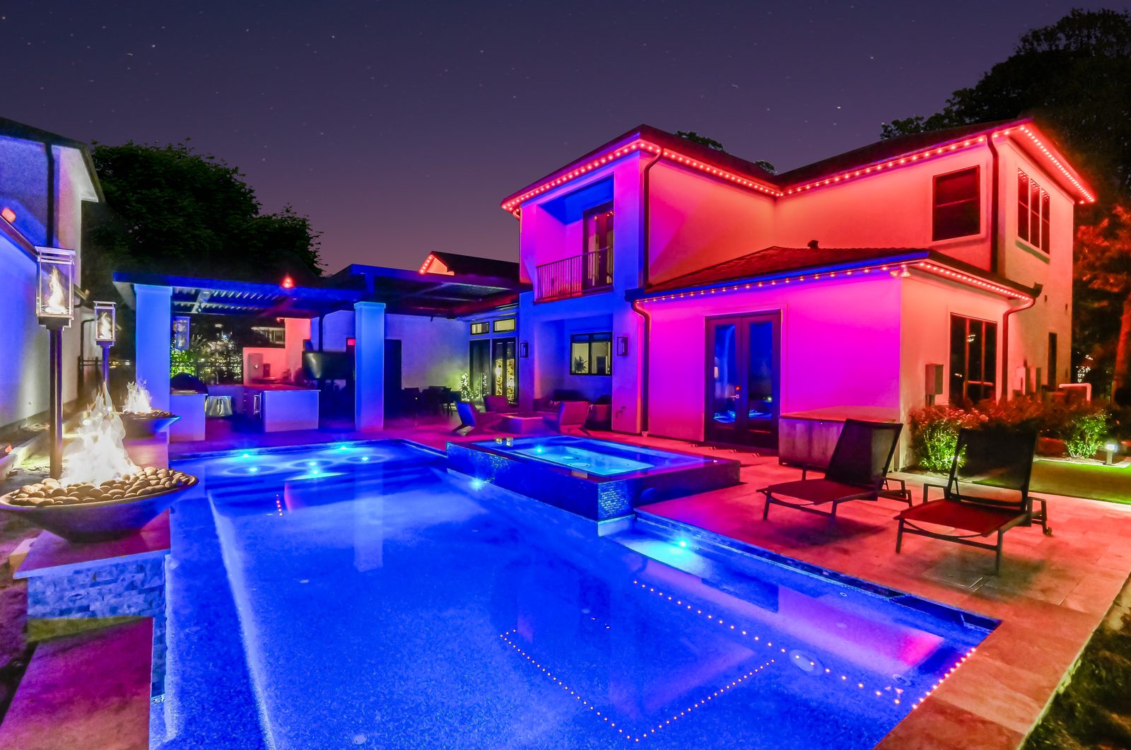 Permanent roofline lighting on a large stone home at night, the style common across Stone Oak, San Antonio